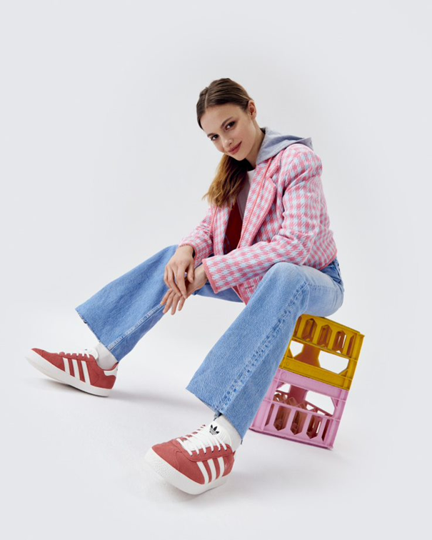 Сниката представя седнало момиче, облечено с дънки и червени маратонки adidas