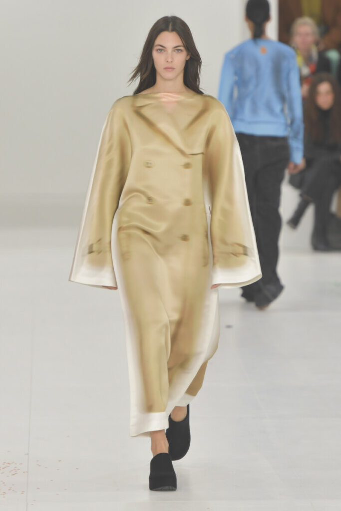 Моделът е облечен с рокля напаодобяваща шлифер на марка Loewe