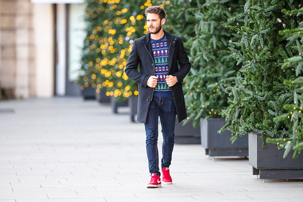 Мъж с коледен пуловер и червени маратонки Nike